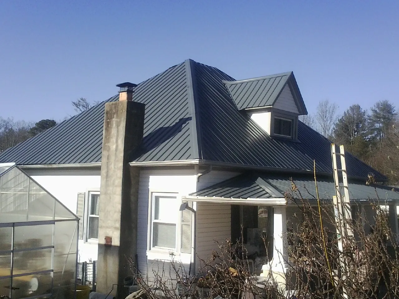 Dark blue standing seam metal roof on a white farmhouse with dormer — Slate & Tile Roof Repair by Roofing Brothers in Sodus Point