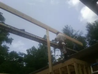 Carpenter setting a ridge beam over a new addition frame — Ice Dam Removal by Roofing Brothers in Sodus Point