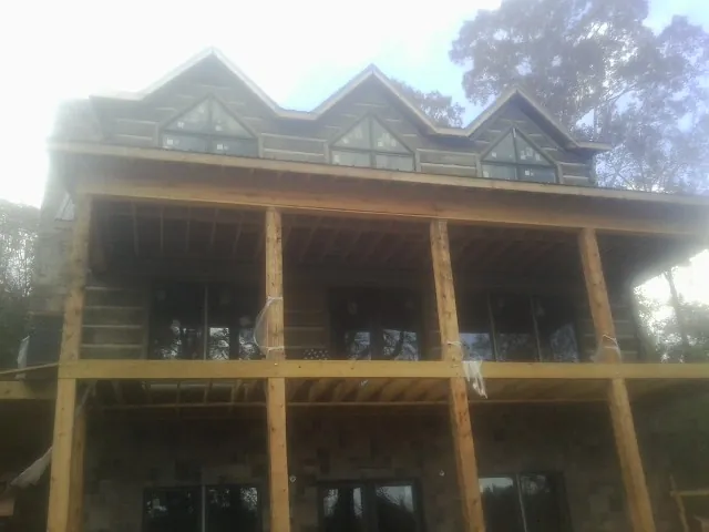 Dormers and porch framing on a large log home under construction — Roof Coating work by our crew in Sodus Point