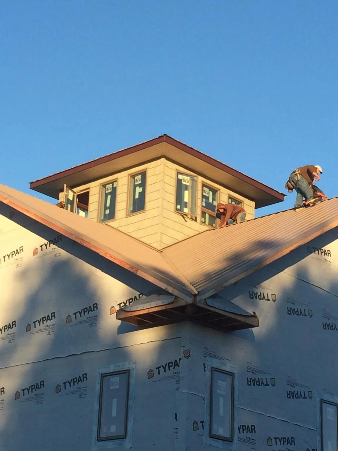 Roofers working around a rooftop cupola on a new metal roof at sunset — Roof Waterproofing in Sodus Point by Roofing Brothers